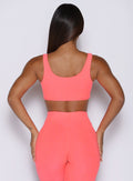 back profile view of a model wearing the Dualmode Bra in neon apricot pink color