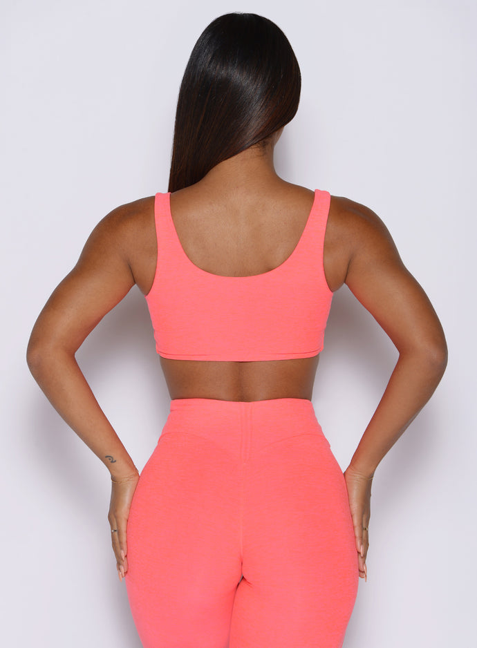 back profile view of a model wearing the Dualmode Bra in neon apricot pink color
