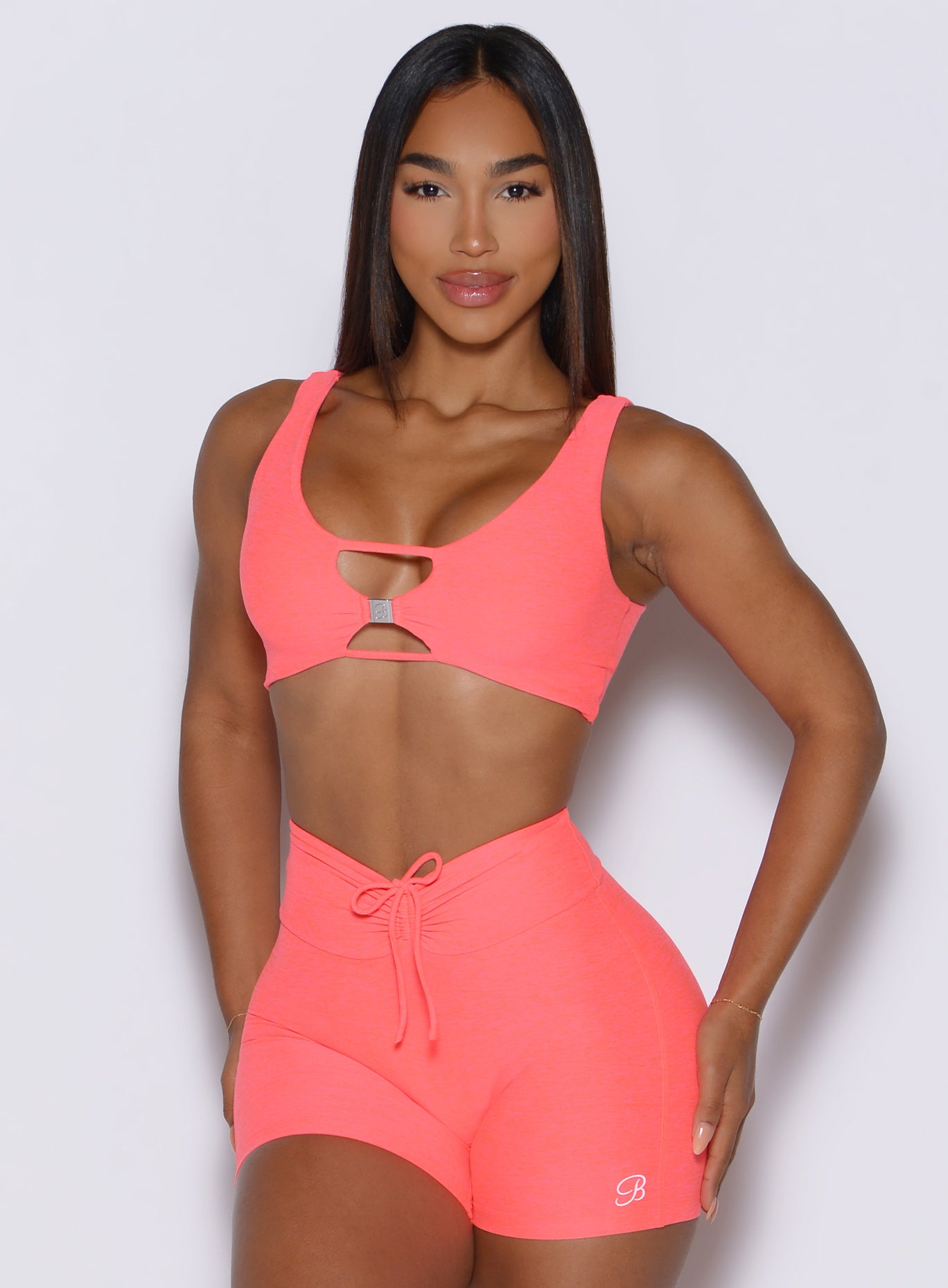 picture showcasing the two way style the Dualmode Bra in neon apricot pink color can be worn while highlighting the B logo in front