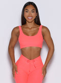 front view of a model wearing the Dualmode Bra in neon apricot pink color without the B logo in front