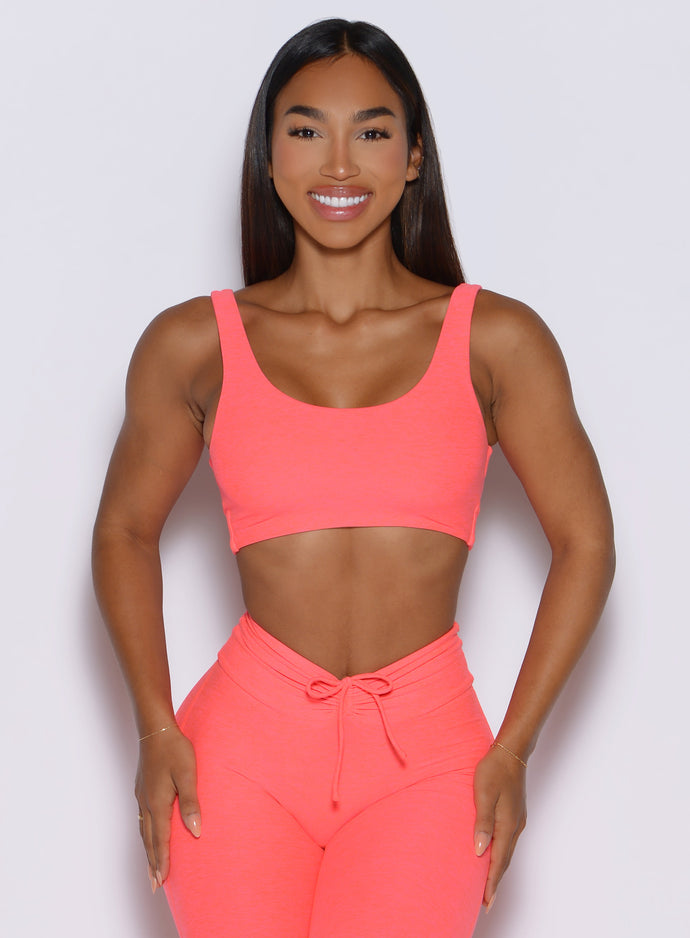 front view of a model wearing the Dualmode Bra in neon apricot pink color without the B logo in front