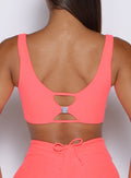 close up back profile view of a model with the B logo on the Dualmode Bra in neon apricot pink color