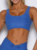 front profile view of a model wearing the Dualmode Bra in neon blue rave color  with the plain side in front. 
