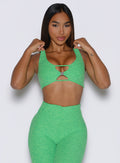 front side view of a model holding the waistband of the shorts wearing the Dualmode Bra in neon miami beach color  