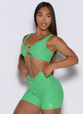front left side profile view of a model holding the waistband of the shorts wearing the Dualmode Bra in neon miami beach color  