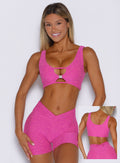 front profile view of a model wearing the Dualmode Bra in neon pink sorbet color with the B logo in front and highlighting the plain side on the back side