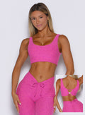 front profile view of a model wearing the Dualmode Bra in neon pink sorbet color with the plain side in front while highlighting the B logo on the back side. 