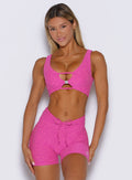 Woman wearing a pink sports bra and shorts set against a white background