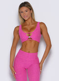 front profile view of a model looking over her shoulder wearing the Dualmode Bra in neon pink sorbet color 