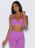 front profile view of a model with one hand on the bra strap wearing the Electric Era Bra in Purple rain color