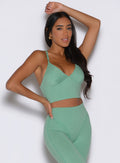 front view of a model with one hand on her waist and the other on top of her head wearing the Electric Era Top in sage color