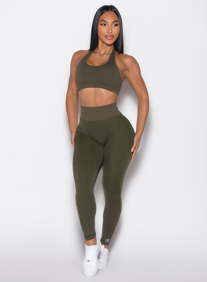 front profile view of a model looking to the right side wearing the Figure Butt Lift Leggings in forest night color