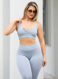 front profile picture of a model wearing sunglasses in our Snap Seamless Bra and the matching leggings in Carbon color