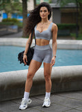 outdoor front profile view of a model wearing our Snap Seamless Bra and the matching shorts in Carbon color