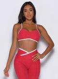 front profile view of a model with one hand on her waist wearing the Finish Line Bra in Raspberry Punch color