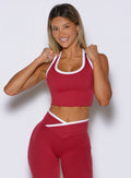 front view of a model holding both the straps wearing the Finish Line Tank in maroon color