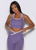 front profile view of a model adjusting the waistband of the leggings wearing the Finish Line Tank in Violet color