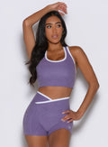 front profile view of a model with one hand resting on top of her head and the other hand on her waist wearing the Finish Line Tank in Violet color
