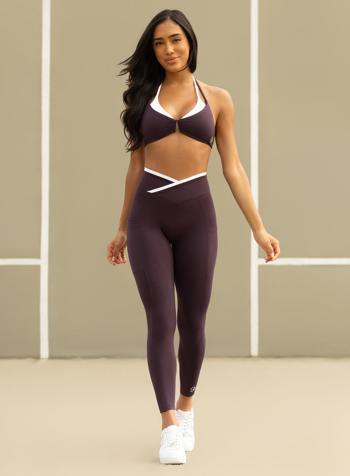 front view of a model in outdoors wearing the Contrast Voltage Sports Bra in black orchid color paired with the matching leggings 