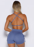 back profile view of a model wearing the FitBoost Bra in Blue slate color paired with the matching shorts 