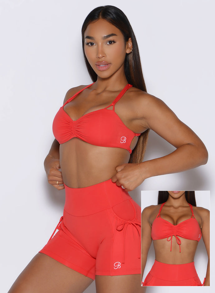 front profile view of a model showcasing the tied and non tied version of the front strap on the FitBoost Bra in Command Red color