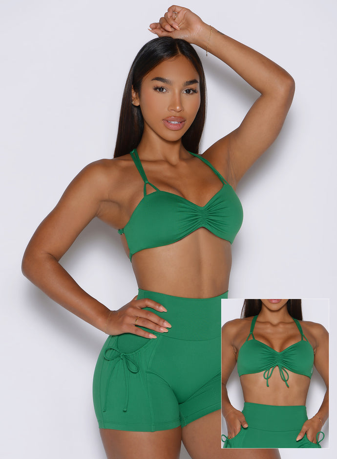front profile view of a model showcasing the tied and non tied version of the front straps wearing the FitBoost Bra in Field Green color