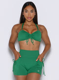 frontal view of a model with both hands inside the pockets of the shorts wearing the FitBoost Bra in Field Green color 