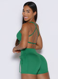 left side profile view of a model looking over her shoulder wearing the FitBoost Bra in Field Green color