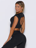 left side profile view of a model looking over her shoulder wearing the FitBoost Tee in Black color