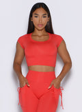 front profile view of a model with both hands inside the pockets of the matching leggings wearing the FitBoost Tee in Command red color