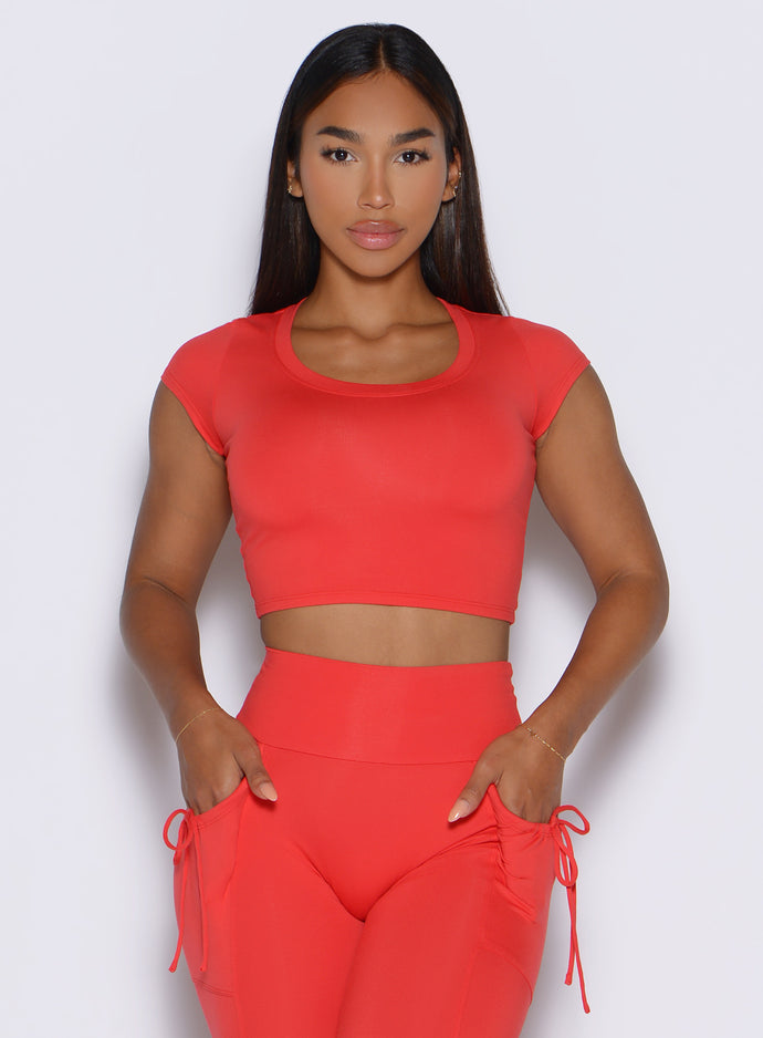 front profile view of a model with both hands inside the pockets of the matching leggings wearing the FitBoost Tee in Command red color