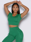 front profile view of a model with both hands resting on top of her head wearing the FitBoost Tee in Field green color