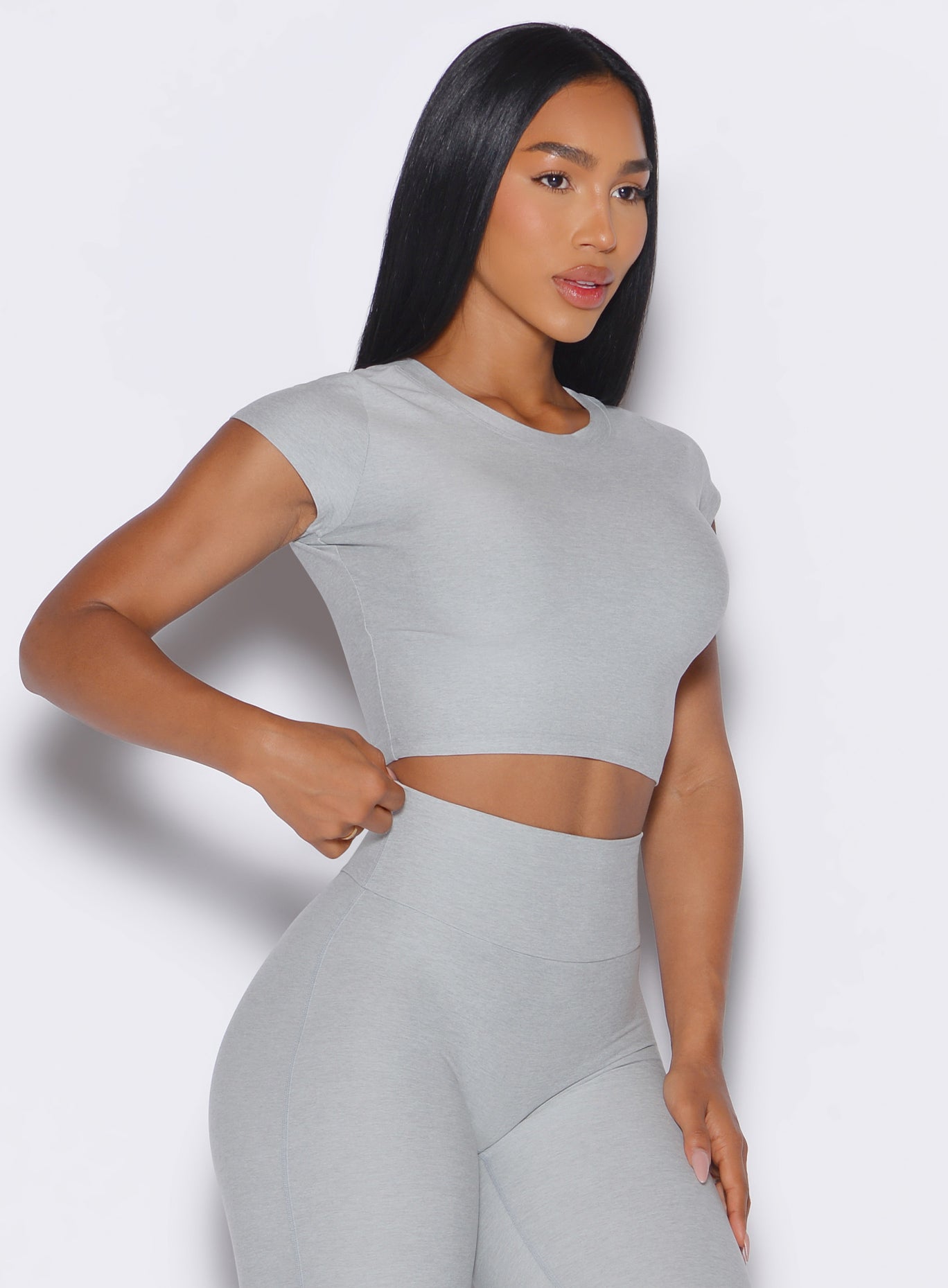 front right side profile view of a model wearing our Fit Fam Active Tee in cloud color along with the matching Leggings