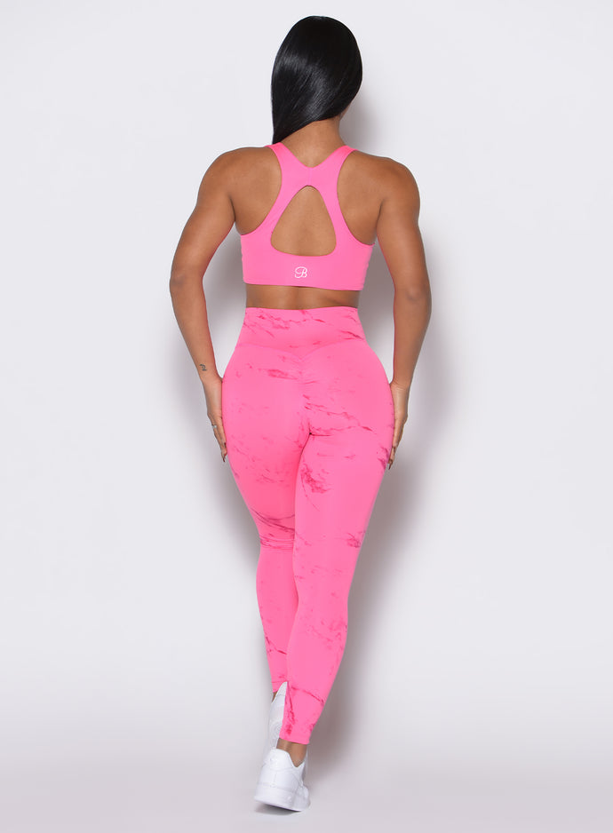 back profile view of a model wearing our fit marble leggings in Cotton Candy Skies color along with a matching bra