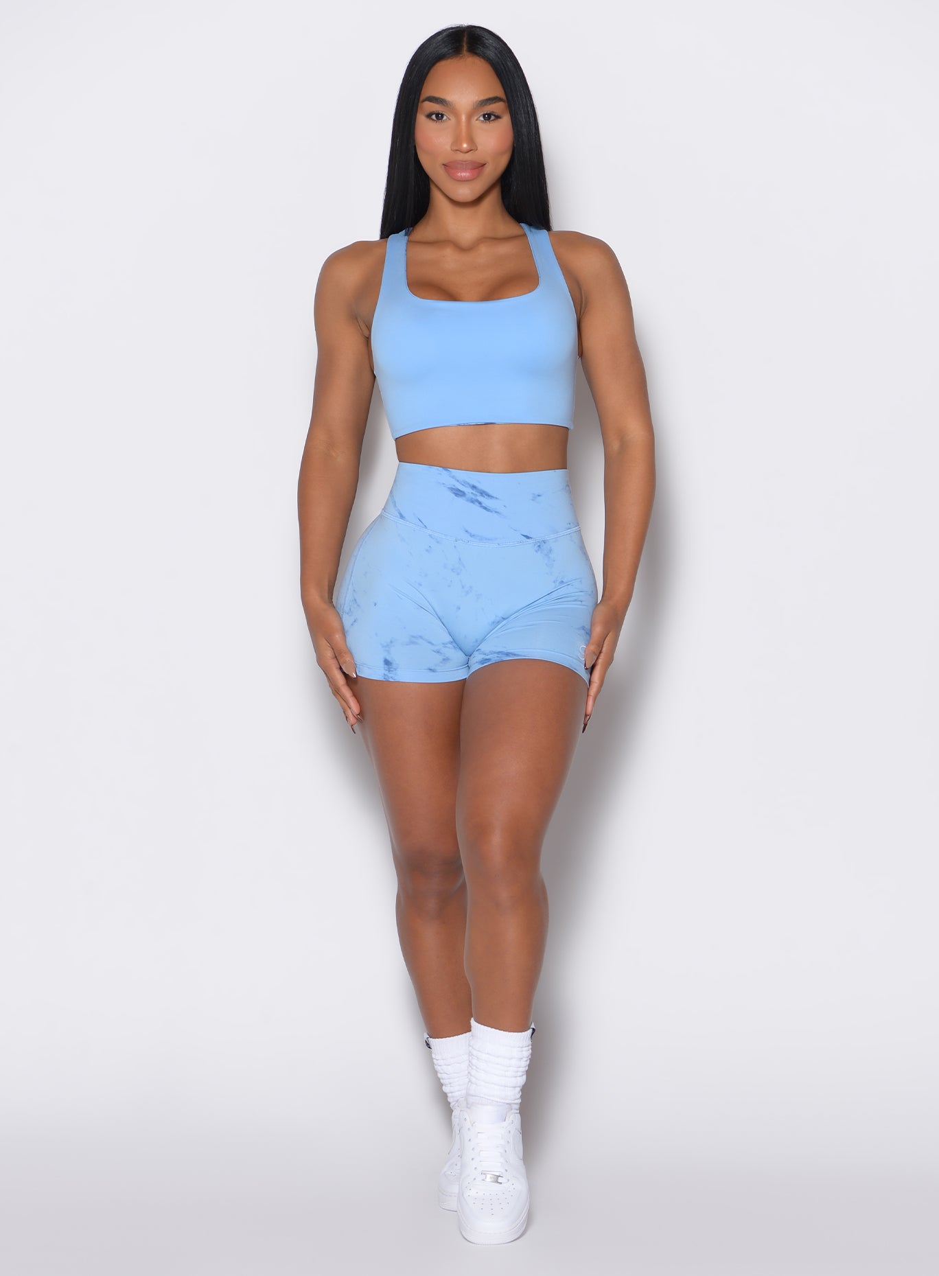 model facing forward wearing our fit marble shorts in blue jay color along with the matching sports bra