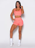 model facing forward wearing our fit marble shorts in Coral reef color along with a matching bra
