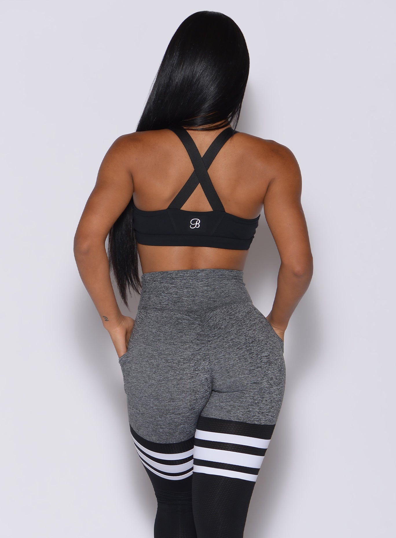 back profile view of a model in our black glow sports bra and a matching thigh high leggings