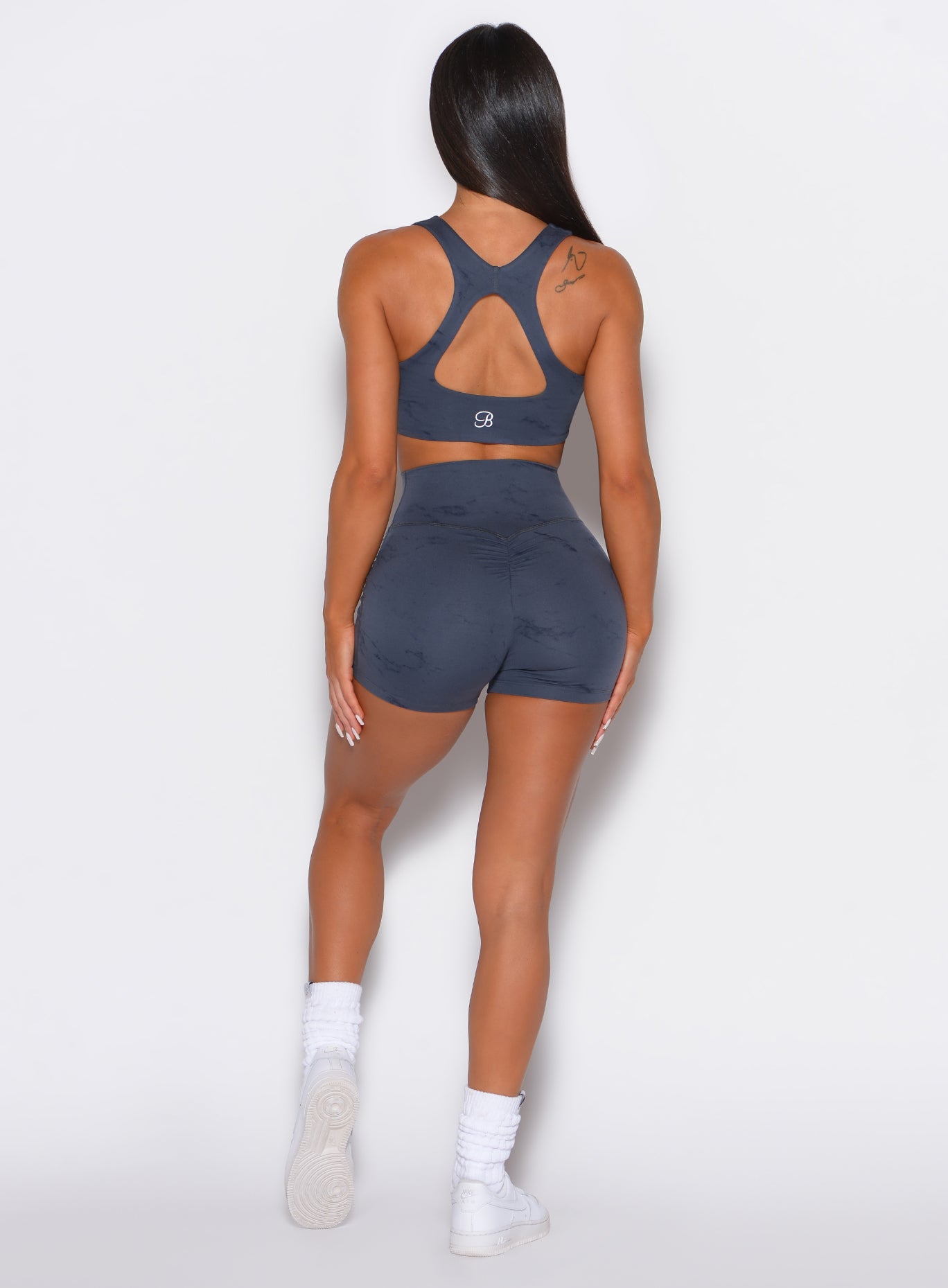 back profile picture of a model wearing our fit marble shorts in thunder gray color along with the matching bra