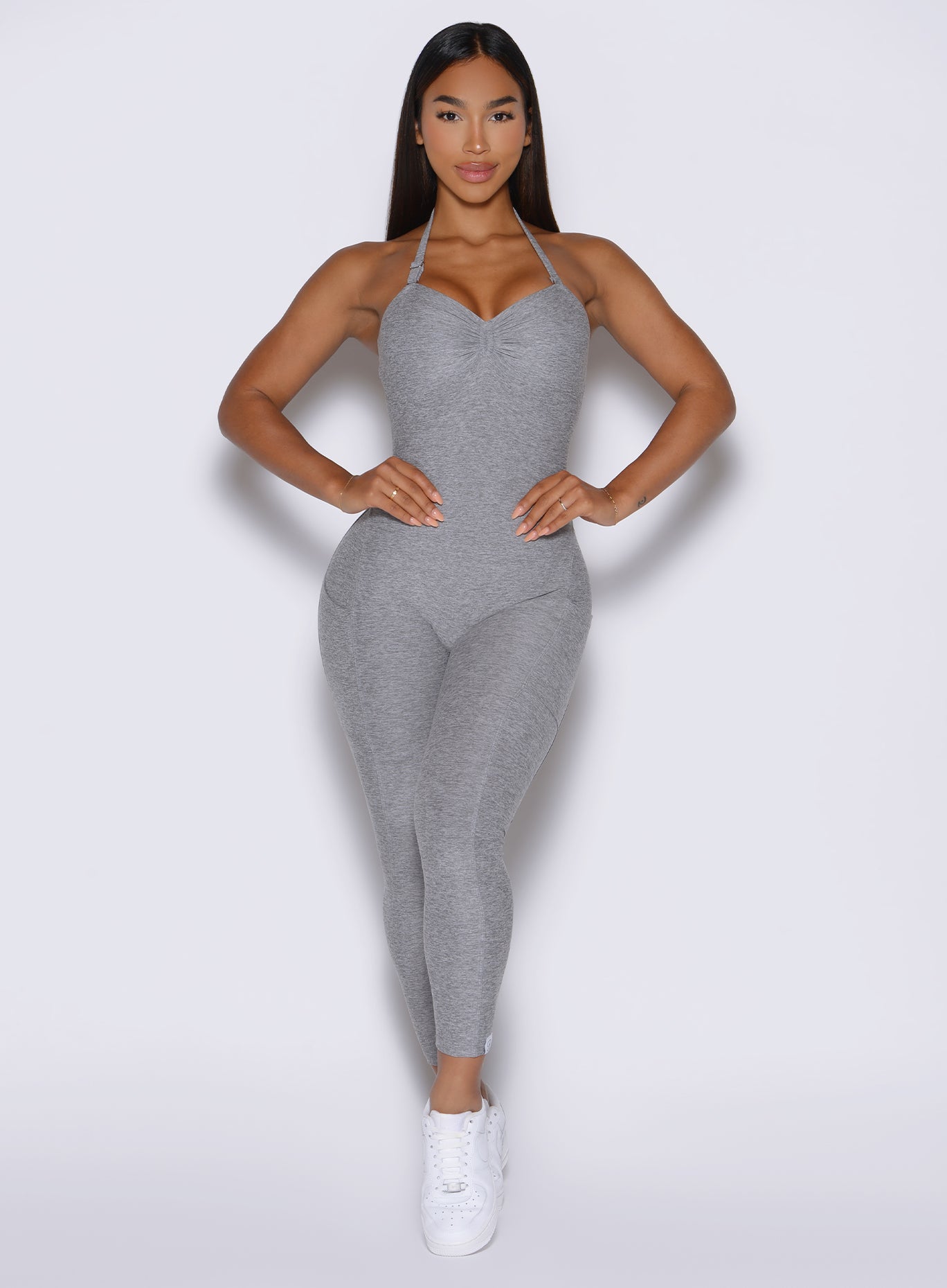 front view of a model with both hands on her waist wearing the flawless form bodysuit in dark and stormy color