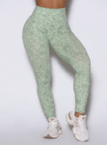 Close-up front shot of the model wearing Flexfit leggings in Leopard Cool Matcha. right leg lifted onto her toes.