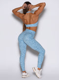 Back profile shot of the model with both her hands resting behind her head wearing our Flexfit leggings in Leopard Glacial Blue paired with a matching top.