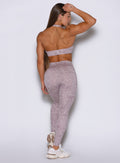 Back profile view of the model with her right hand raised over her head wearing our Flexfit leggings in Leopard Violet Ice paired with the matching top.