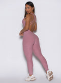 back left side profile view of a model looking over her shoulder wearing the Form Bodysuit in Rose/Blush color