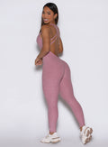 left side shot of a model wearing the Form Bodysuit in Rose/Blush color