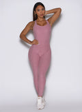 front profile view of a model with one hand on her waist wearing the Form Bodysuit in Rose/Blush color