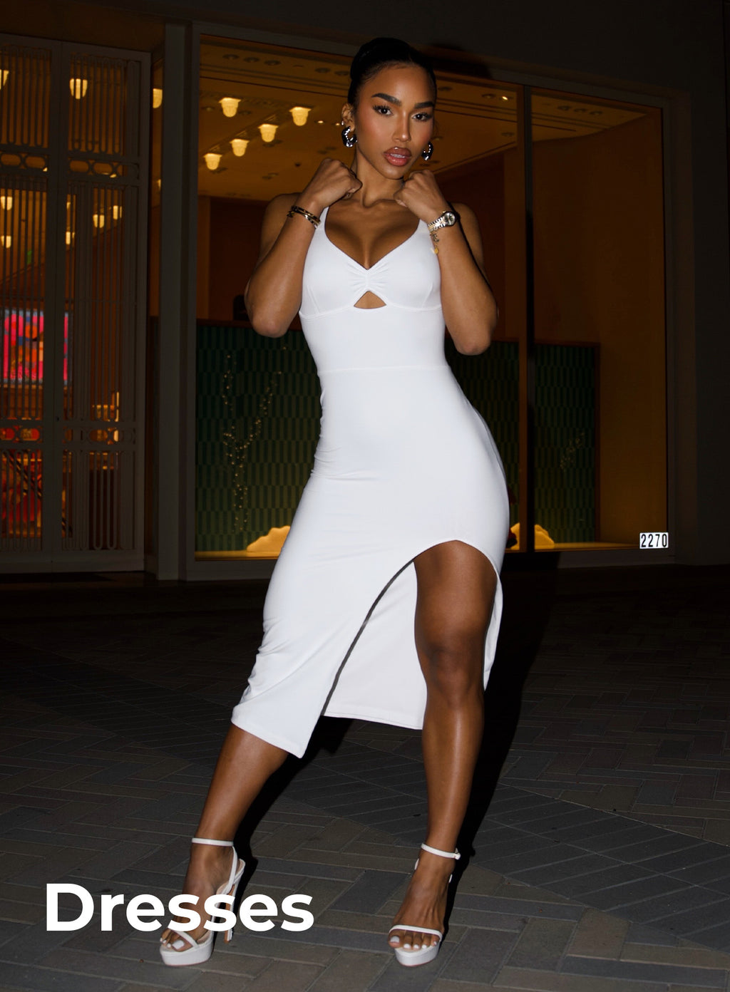 Front full body image of model in white dress and heels with text in bottom left corner that reads "Dresses"
