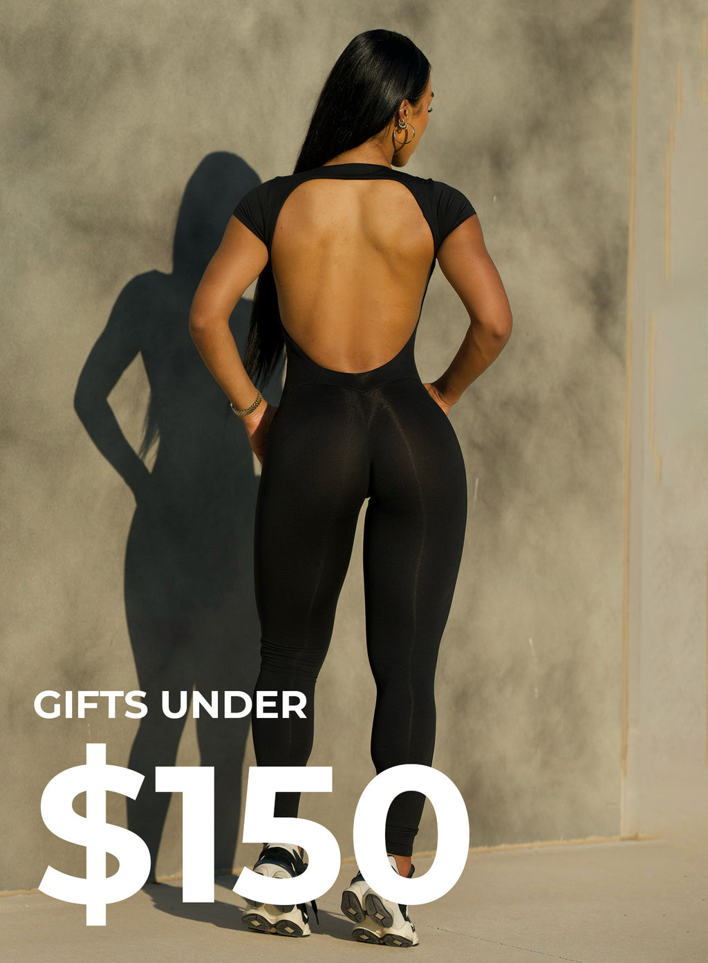 Back view of model wearing black bodysuit. bottom left corner says GIFTS UNDER $150 in white text