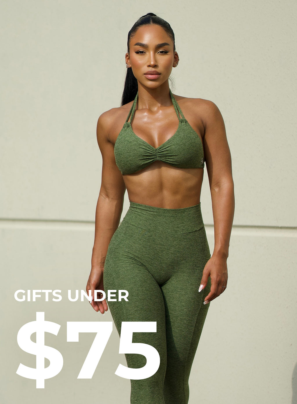 Front view of model wearing green active set. bottom left corner says GIFTS UNDER $75 in white text