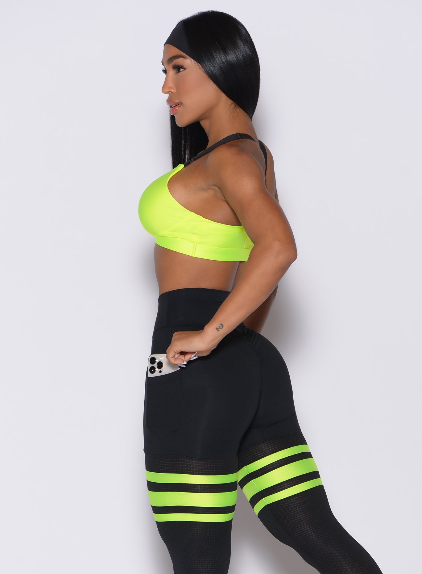 Left side profile view of a model in our glow sports bra in neon yellow and a matching leggings