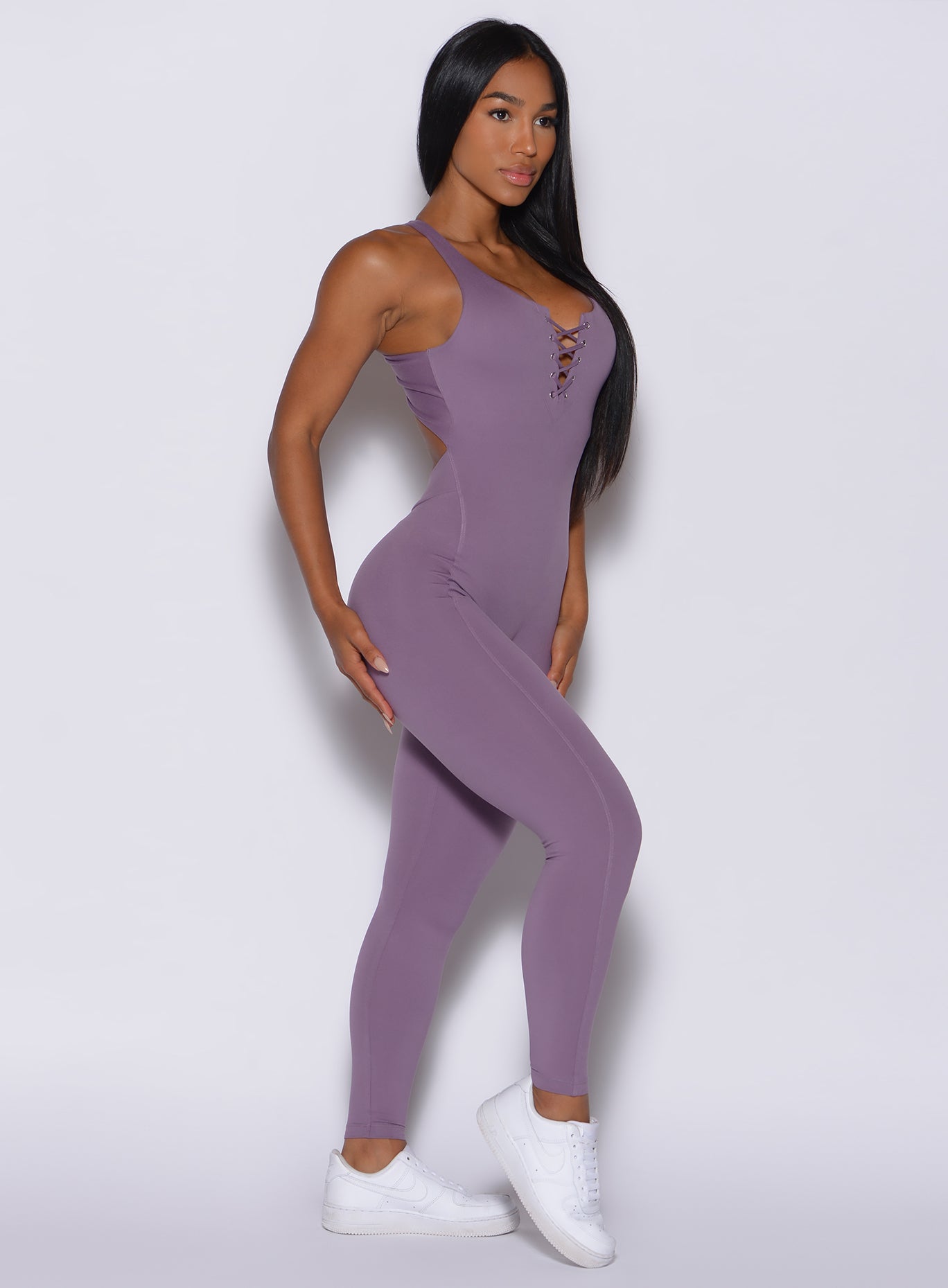 Right side profile view of a model wearing our laced bodysuit in Violet Frost color